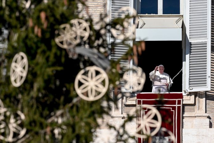 Pope Francis waves to worshippers from the window of the apostolic palace overlooking St. Peter's Square and the Vatican's Christmas Tree (left) during the weekly Angelus prayer on Dec. 13, in the Vatican. (Photo by Vincenzo Pinto/AFP)