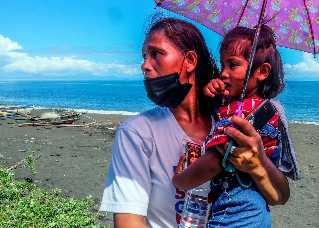 Annalisa Capa, 44, carries her three-year-old daughter on the shore of Baybay village in the town of Malinao, Albay. (Photo by Marielle Lucenio)