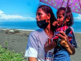 Annalisa Capa, 44, carries her three-year-old daughter on the shore of Baybay village in the town of Malinao, Albay. (Photo by Marielle Lucenio)
