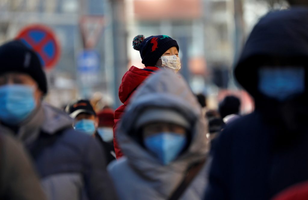 FILE PHOTO: People wearing masks walk in a street in Beijing's CBD during morning rush hour