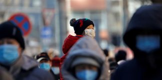FILE PHOTO: People wearing masks walk in a street in Beijing's CBD during morning rush hour
