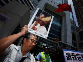 A protester carries a portrait of Bishop Su Zhi-ming of Baoding, Hebei province, who has been imprisoned in China and is now unreachable, during a protest demanding religious freedom outside China Liaison Office in Hong Kong July 11, 2012. (Reuters file photo)