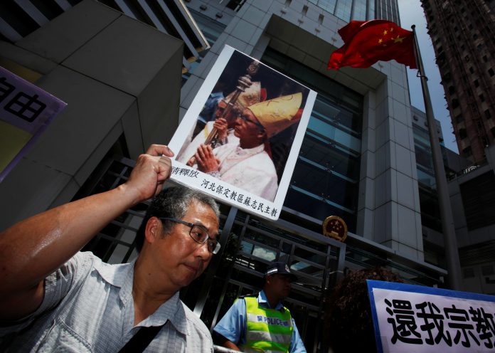 A protester carries a portrait of Bishop Su Zhi-ming of Baoding, Hebei province, who has been imprisoned in China and is now unreachable, during a protest demanding religious freedom outside China Liaison Office in Hong Kong July 11, 2012. (Reuters file photo)