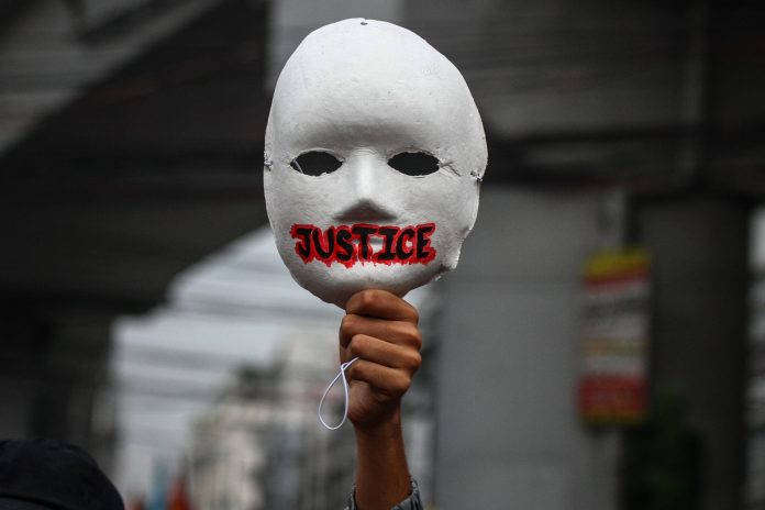 A activist raises a mask during an International Human Rights Day march in Manila on Dec. 10, 2020, to call for justice to alleged human rights abuses committed by state forces. (Photo by Jire Carreon)