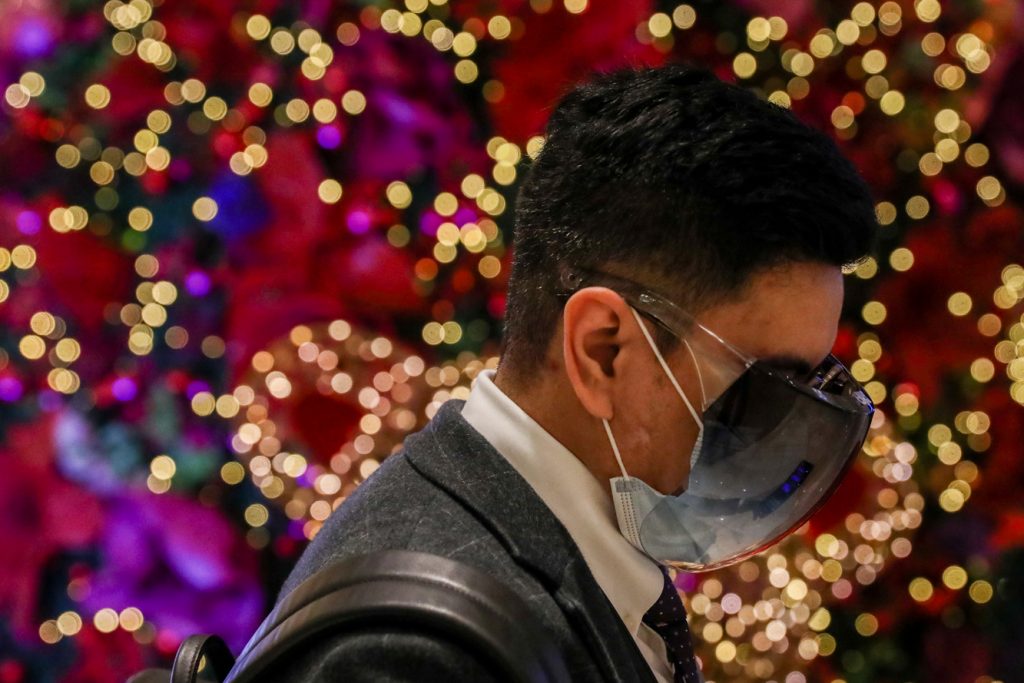 A man wearing protective mask and face shield walks inside a mall with Christmas decorations in the Philippine capital. (Photo by Basilio Sepe)