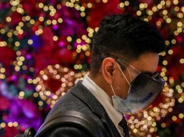 A man wearing protective mask and face shield walks inside a mall with Christmas decorations in the Philippine capital. (Photo by Basilio Sepe)