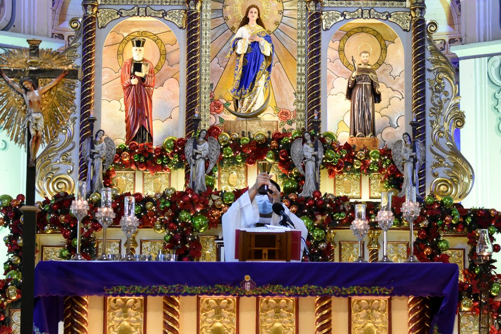 Father Hans Magdurulang celebrates early morning Mass at San Felipe Neri Parish in Mandaluyong City in the Philippine capital on Dec. 23. (Photo by Angie de Silva)