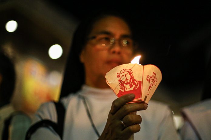 A Catholic nun holds a candle during a 2019 demonstration in Manila to call for peace and an end to human rights violations in the country. (File photo by Jire Carreon)