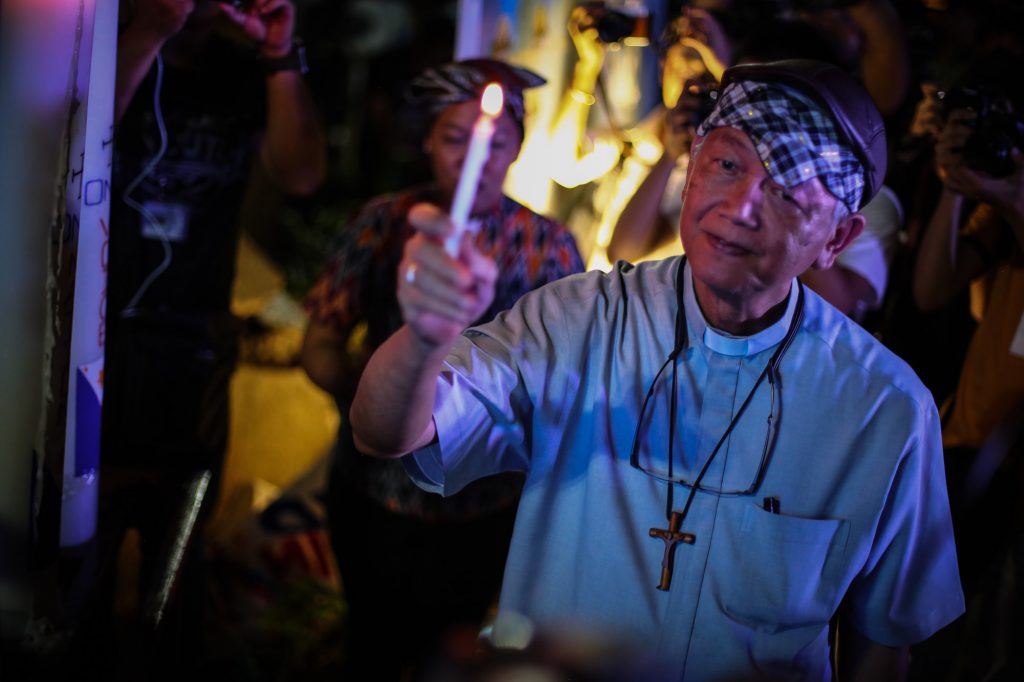 Bishop Broderick Pabillo, apostolic administrator of the Archdiocese of Manila, holds a candle during a demonstration in Manila in 2019. (Photo by Jire Carreon)