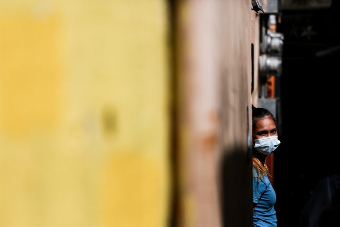 A woman wearing a protective mask steps out from her house in the Philippine capital as the country continues to experience an increase in COVID-19 cases. (Photo by Basilio Sepe)