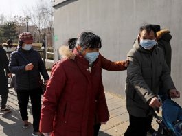 People wearing face masks walk along a street, following reports of new COVID-19 cases in Beijing, China on Jan. 11. (Photo by Tingshu Wang/Reuters)