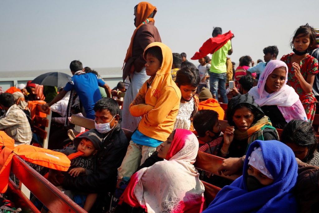 Rohingya refugees sit on wooden benches of a navy vessel on their way to the Bhasan Char island in Noakhali district