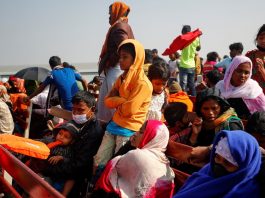 Rohingya refugees sit on wooden benches of a navy vessel on their way to the Bhasan Char island in Noakhali district