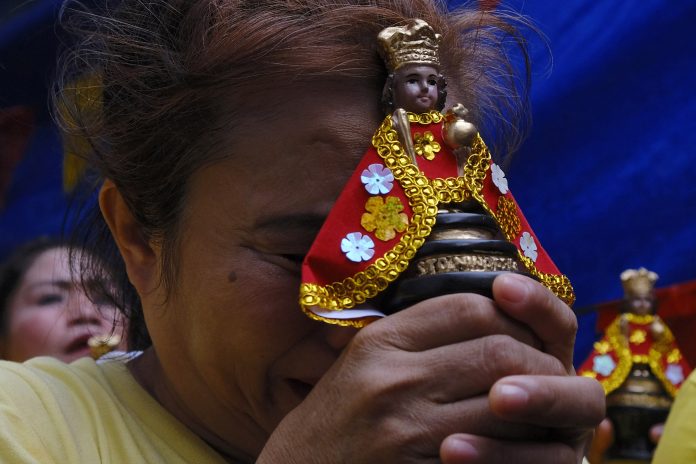 A devotee of the Child Jesus holds an image of the Santo Niño while praying in the province of Cebu. (File photo by Victor Kintanar)