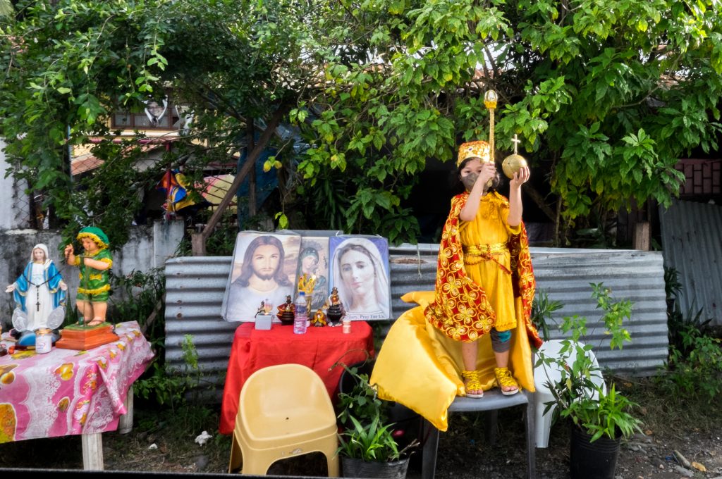 A child dressed as the Santo Niño stands on a plastic chair while awaiting the motorcade of the images of the Child Jesus during the Dinagyang on January 24. (Photo by Marielle Lucenio)