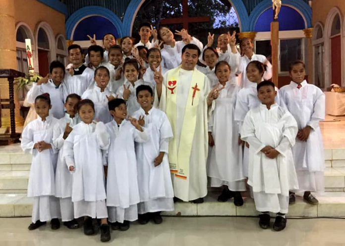 Father Rene Regalado poses with altar servers in this undated photo. (Photo supplied)