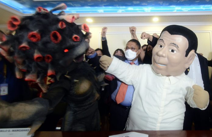 A Duterte mascot hits a representation of the new coronavirus to dramatize the Philippine government’s effort to fight the spread of the disease during a media briefing in the city of Pasay in October. (File photo by Mike Taboy)