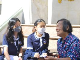 Two female high school students talking with a female bread seller in Thailand